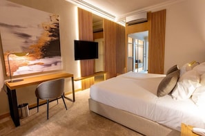 A hotel room with a bed, a desk, a chair, a TV, and a painting on the wall. - Hotel Cidnay (Santo Tirso)