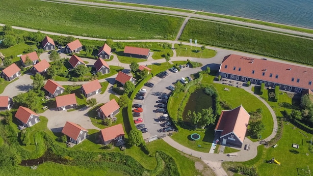 An aerial view of a residential area with houses, a parking lot, and a large building with a red roof. - Beautiful apartment in villa for 5 people with WIFI, TV, terrace and panoramic view (Wemeldinge)