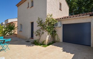 A building with a garage door, a small garden with plants, and a blue chair outside. - Stunning home in Arles (Arles)