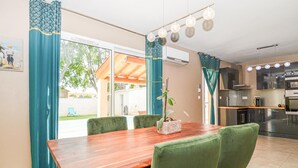 A dining area with a wooden table, green chairs, and a potted plant. - Stunning home in Arles (Arles)