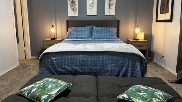 A bedroom with a bed, two bedside tables with lamps, a headboard, a grey sofa with pillows, and three wall-mounted feather art pieces. - Comfortable 3BR Home w/ POOL! Near Lackland AFB & Seaworld for BMT Families (San Antonio)