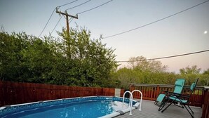 A swimming pool on a wooden deck with a wooden fence and green chairs. - Comfortable 3BR Home w/ POOL! Near Lackland AFB & Seaworld for BMT Families (San Antonio)