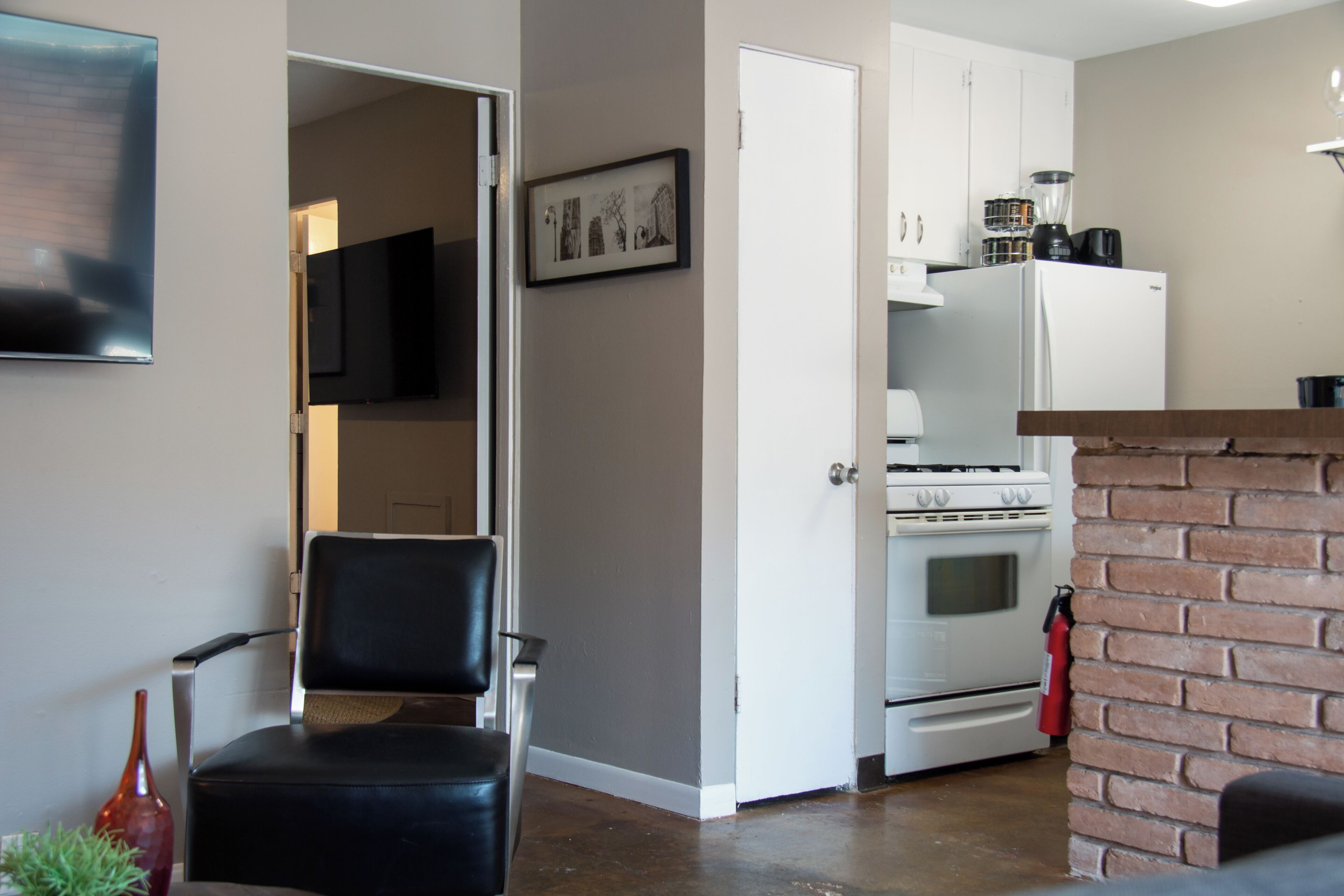 A compact kitchen with a stove, refrigerator, and a brick accent wall.