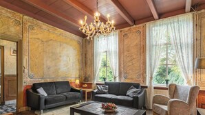 Une pièce avec un lustre, deux canapés, une table basse et un fauteuil à motifs.