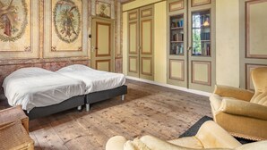 Une chambre avec deux lits, une bibliothèque et une grande fenêtre.