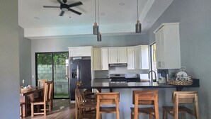 Een moderne keuken met houten stoelen, een centraal kookeiland en een plafondventilator.