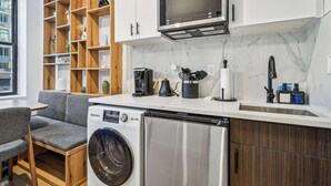 Uma cozinha compacta com máquina de lavar embutida, micro-ondas e cafeteira.