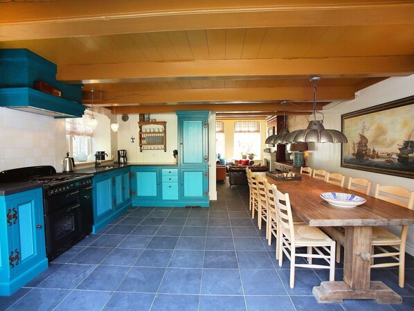 A kitchen with blue cabinets, a dining table with chairs, and a painting on the wall.