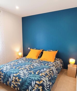 Une chambre à coucher avec un lit, deux lampes de chevet et un mur bleu.