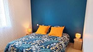 Ein Schlafzimmer mit einem Bett, zwei Nachttischlampen und einem Fenster mit Vorhängen.