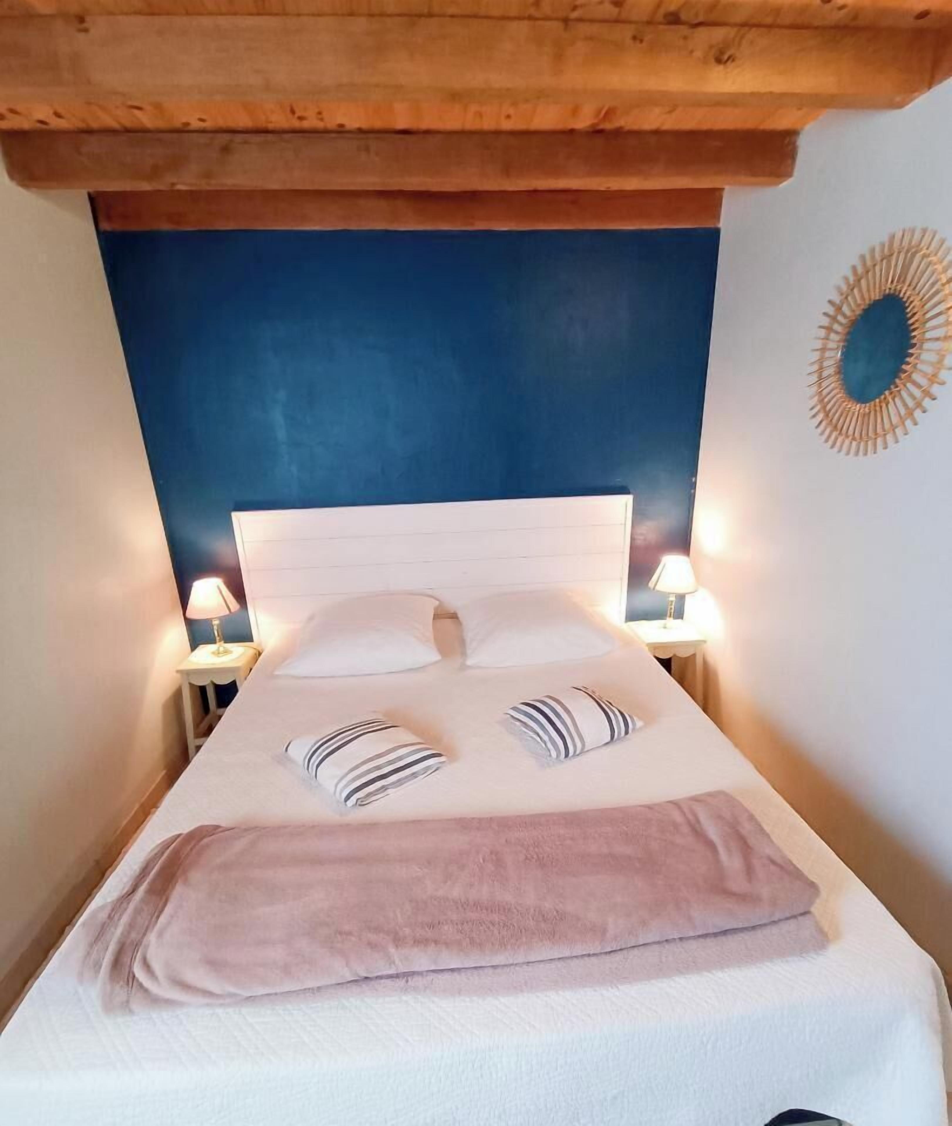 A bed with a wooden headboard, two bedside lamps, and a decorative mirror on the wall.