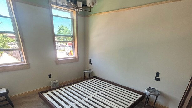 A room with a large bed, two windows, a ceiling light fixture, and a small stool. - Maison Kesh (Washington)