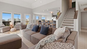 A spacious living area with a sofa set, a dining table, and a staircase. - Serene Coastal Escape With Gulf Views 3 Bedroom Home (Galveston)