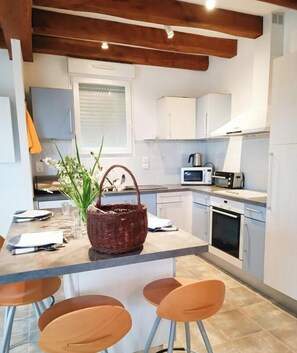 A modern kitchen with a central island, white cabinets, a microwave, and a toaster. - Gîtes de la Gariotte - QUISSAC-EN-QUERCY (QUISSAC-EN-QUERCY)