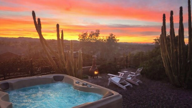 A hot tub with a sunset view, surrounded by cacti and a fire pit.