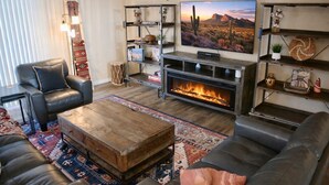 A living room with a fireplace, leather sofas, a coffee table, and a television.