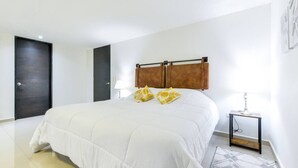 Un dormitorio con cama, mesita de noche, lámpara y puerta.