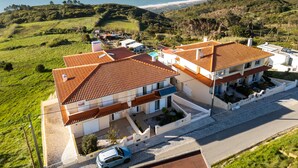 A two-story building with a red-tiled roof, a swimming pool, and a view of the ocean. - Villa Serra e Mar - Holiday home (Serra da Pescaria)
