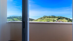 A view from a window with a clear sky, a green hill, and a distant building. - Villa Serra e Mar - Holiday home (Serra da Pescaria)