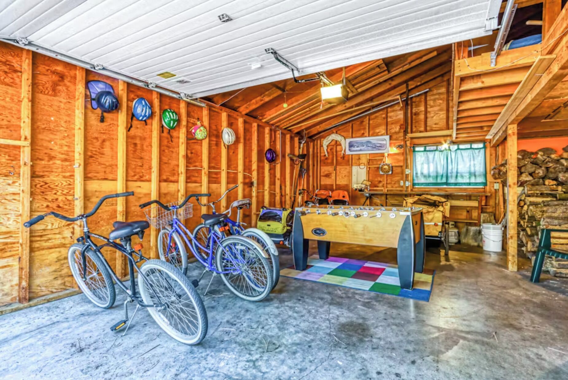 Un intérieur en bois, avec des vélos, une table de baby-foot et une fenêtre avec des rideaux.