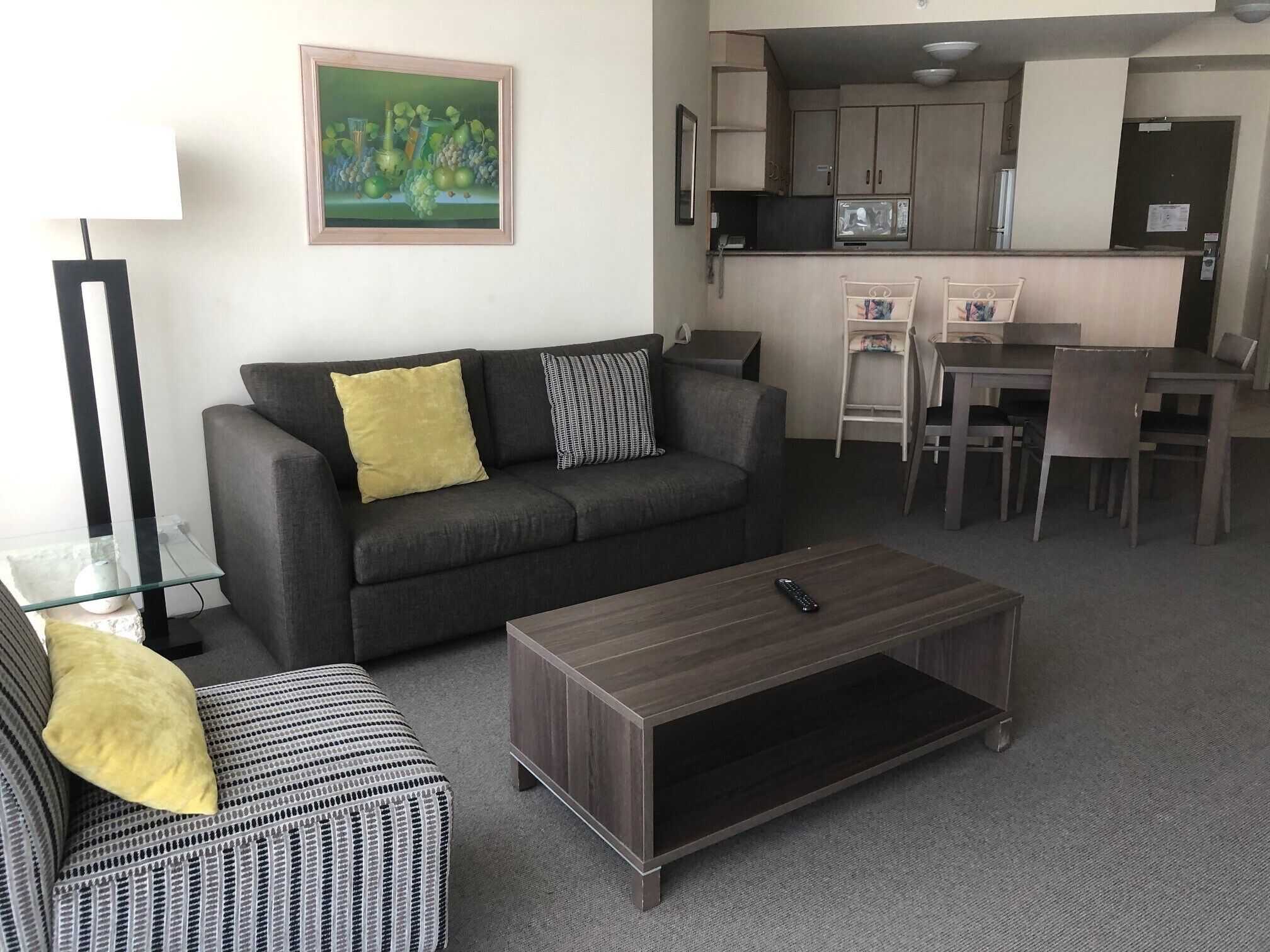Una sala de estar con un sofá, un reposapiés, una mesa de centro y un cuadro en la pared.
