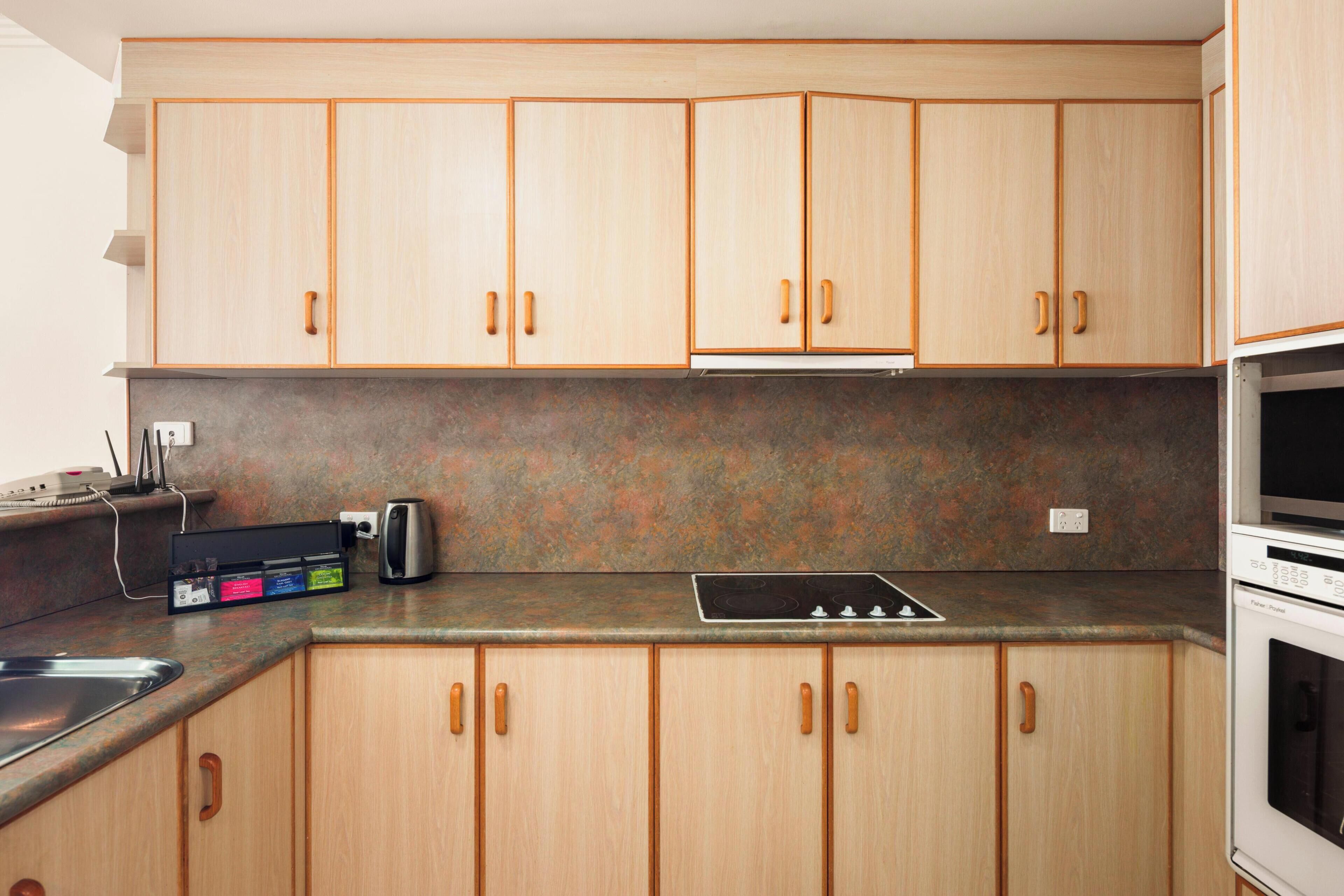 A kitchen with wooden cabinets, a built-in stove, and a sink.