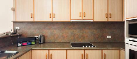 A kitchen with wooden cabinets, a built-in stove, and a sink.