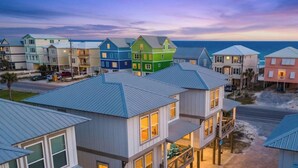 A coastal residential area with colorful houses, a road, and the ocean in the background. - Pelican Haven • Beach Access • Community Pool • Fishing Pier (Gulf Shores)