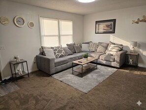 A living room with a grey sofa, a coffee table, a small side table, and a lamp.