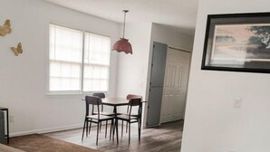 A spacious living area with a dining table, chairs, a hanging light fixture, and a framed picture on the wall. - Second Home Apartment, Close to Everything (Orangeburg)