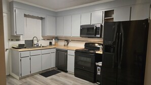 A modern kitchen with white cabinets, a black refrigerator, a microwave, and a stove. - Second Home Apartment, Close to Everything (Orangeburg)