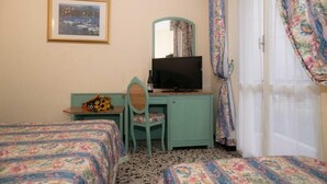 A room with two beds, a desk with a television, a chair, a framed picture on the wall, and a door with curtains. - hotel magnolia (Albenga)