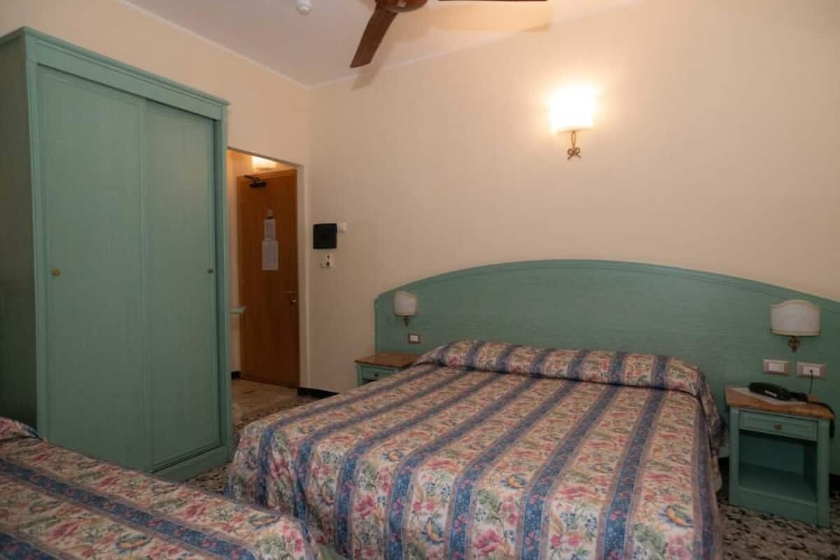 Une chambre à coucher comprenant un lit, une armoire, une table de chevet et un luminaire fixé au mur.
