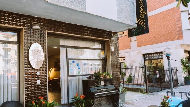 A building with a piano outside, a sign for a self-service lavender shop, and outdoor seating with potted plants. - hotel magnolia (Albenga)