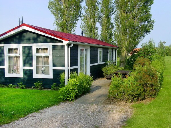 A house with a red roof, white trim, and a gravel path leading to the front door.