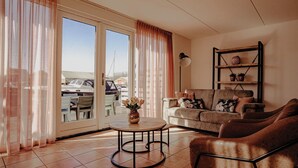 A living room with a sofa, armchair, and a small round table with a vase. - Cosy apartment for 6 guests with WIFI, TV, terrace and pets allowed (Uitgeest)