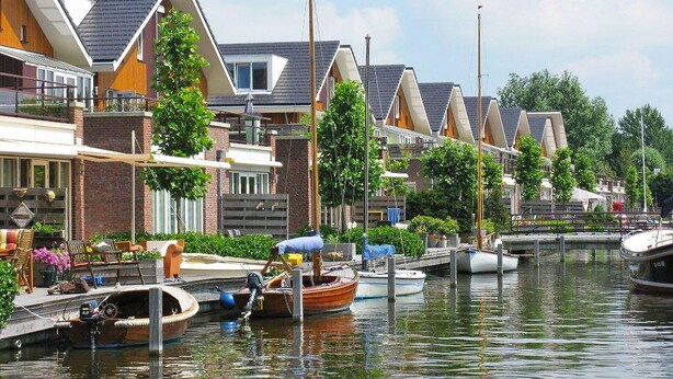 A canal with houses on one side and boats docked along the water. - Cosy apartment for 6 guests with WIFI, TV, terrace and pets allowed (Uitgeest)