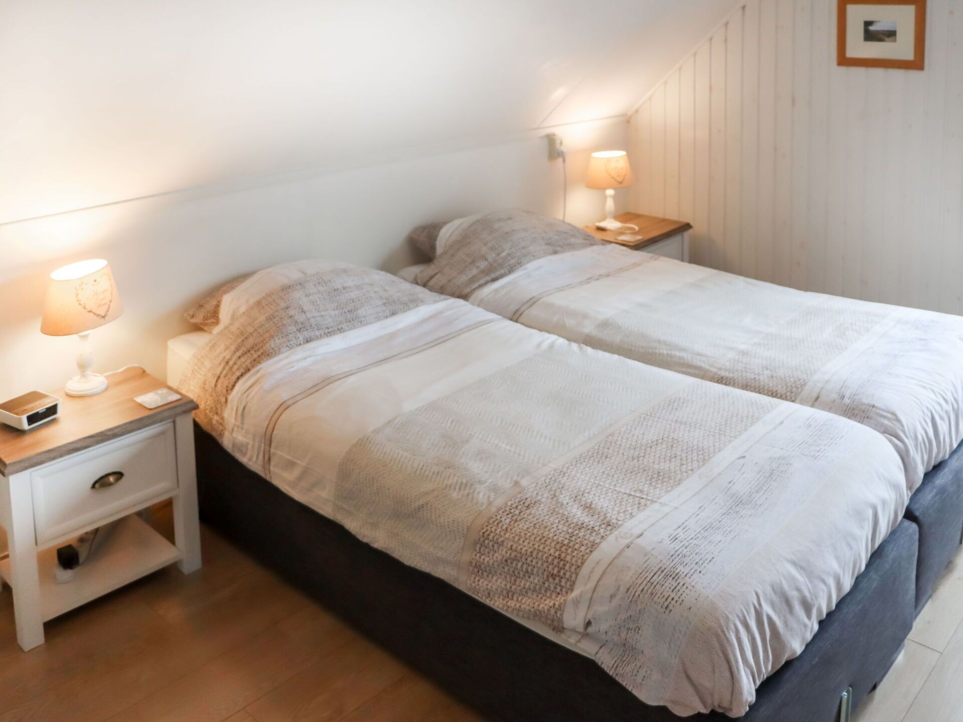 Une chambre à coucher avec un lit double, des tables de chevet avec des lampes, une table de nuit et un tiroir.