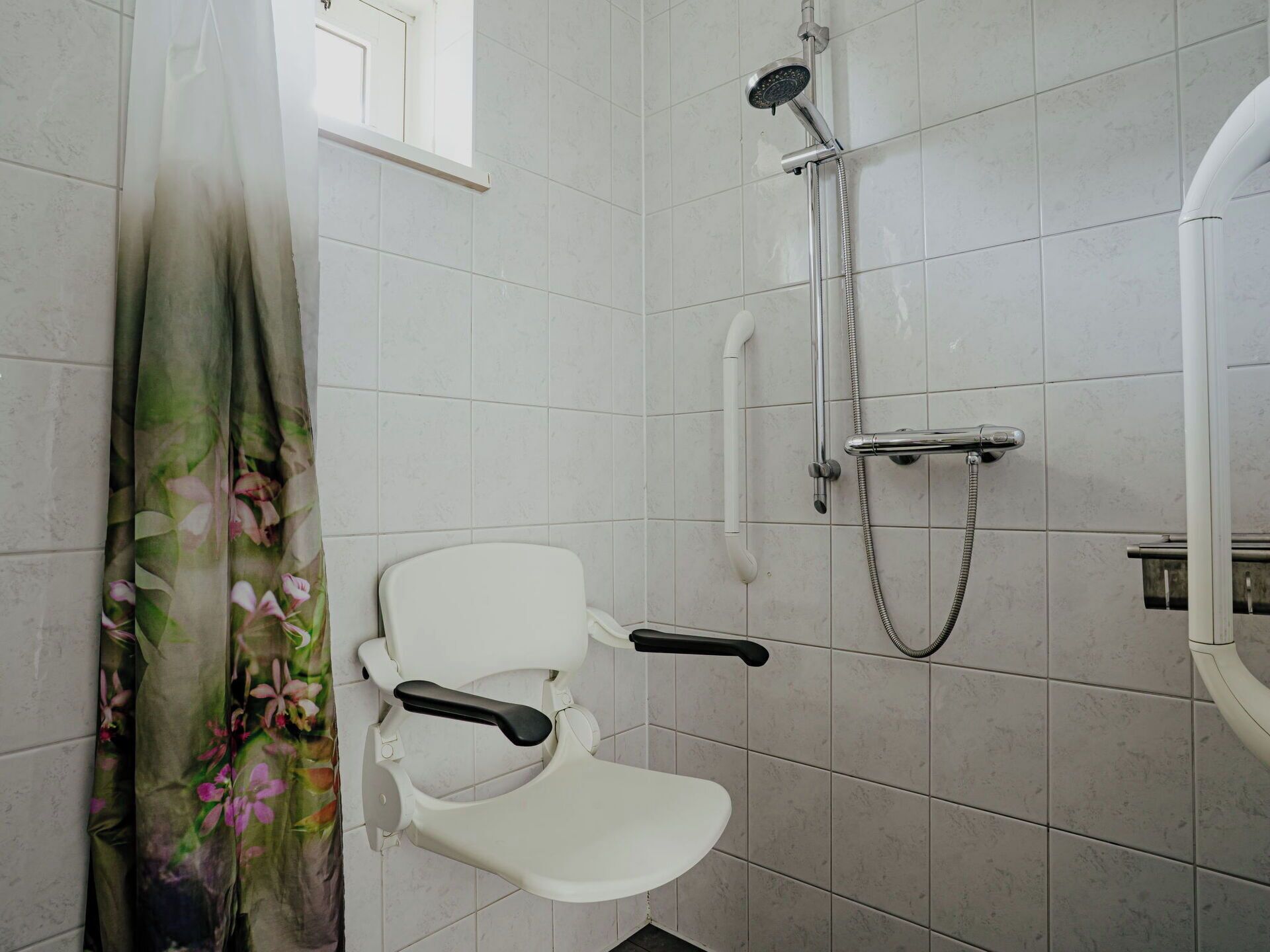 Une salle de bain avec une douche, des toilettes et une fenêtre.