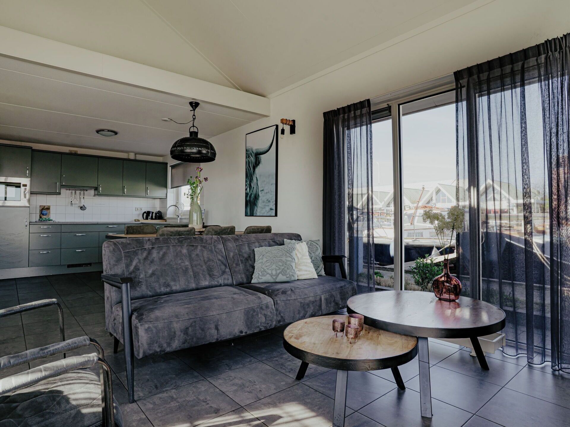 Un espace de vie moderne avec un canapé, une table basse ronde et une cuisine en arrière-plan.
