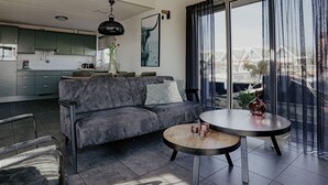 A modern living space with a sofa, a round coffee table, and a kitchen in the background. - Stunning private villa for 6 people with WIFI, TV, terrace and pets allowed (Uitgeest)