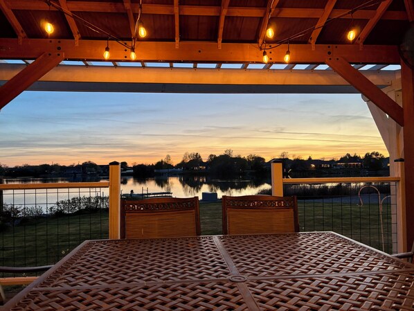 A covered outdoor seating area with a view of a lake and distant buildings. - Lakefront Escape Near Gorge Amphitheater (Moses Lake)