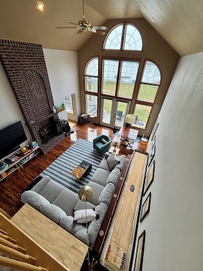 A spacious living room with a fireplace, a large window, a ceiling fan, and a pool table. - Lakefront Escape Near Gorge Amphitheater (Moses Lake)