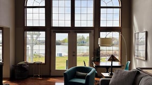 A spacious living room with large arched windows, a comfortable sofa, a small table, and a lamp. - Lakefront Escape Near Gorge Amphitheater (Moses Lake)