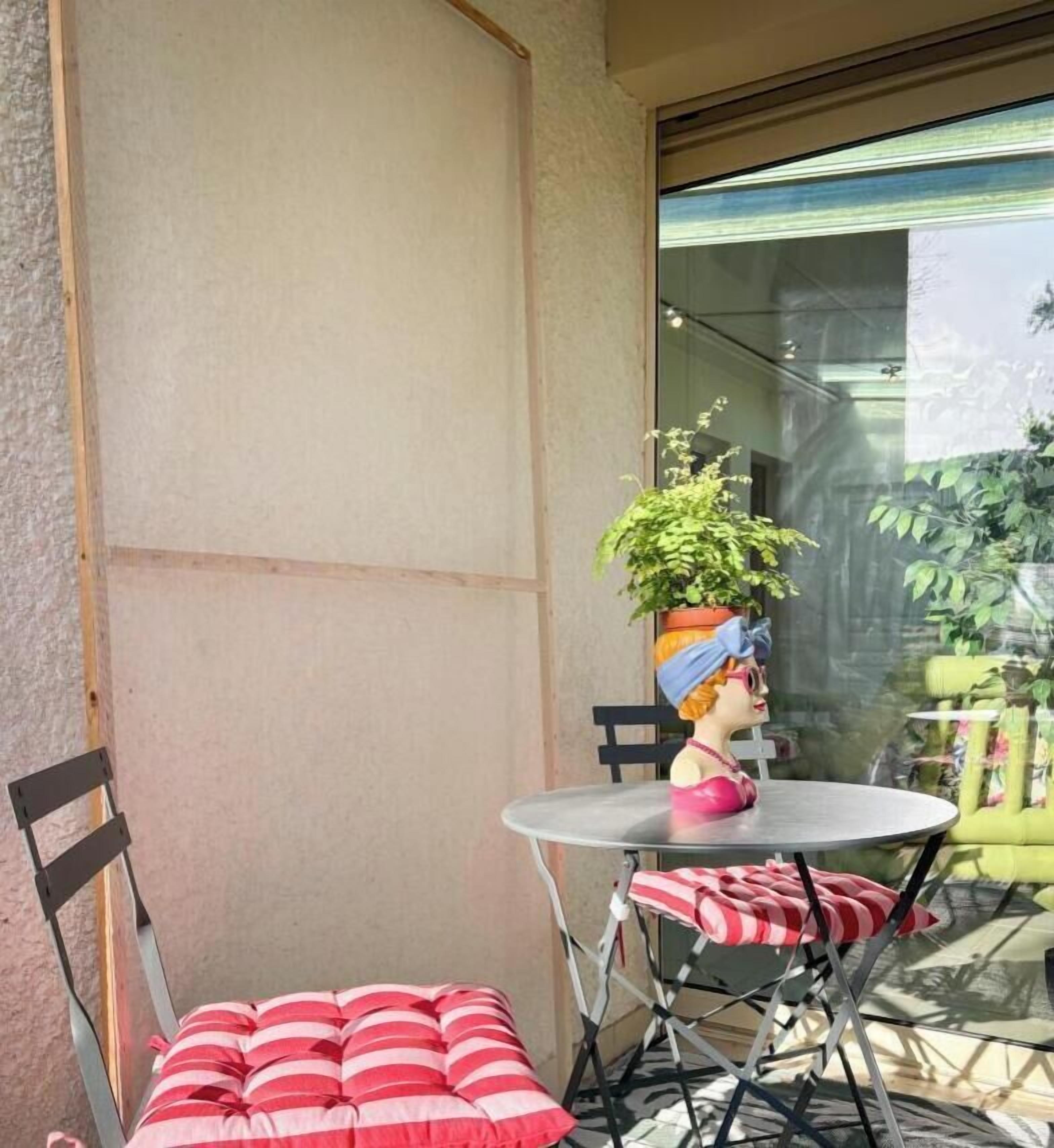A small outdoor seating area with a table, chairs, and a cushion.