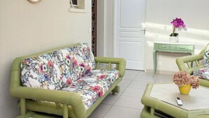 A room with a green sofa, a small table with a vase, a mirror, and a door. - Le Mûrier - GRAMAT - Gîte (GRAMAT)