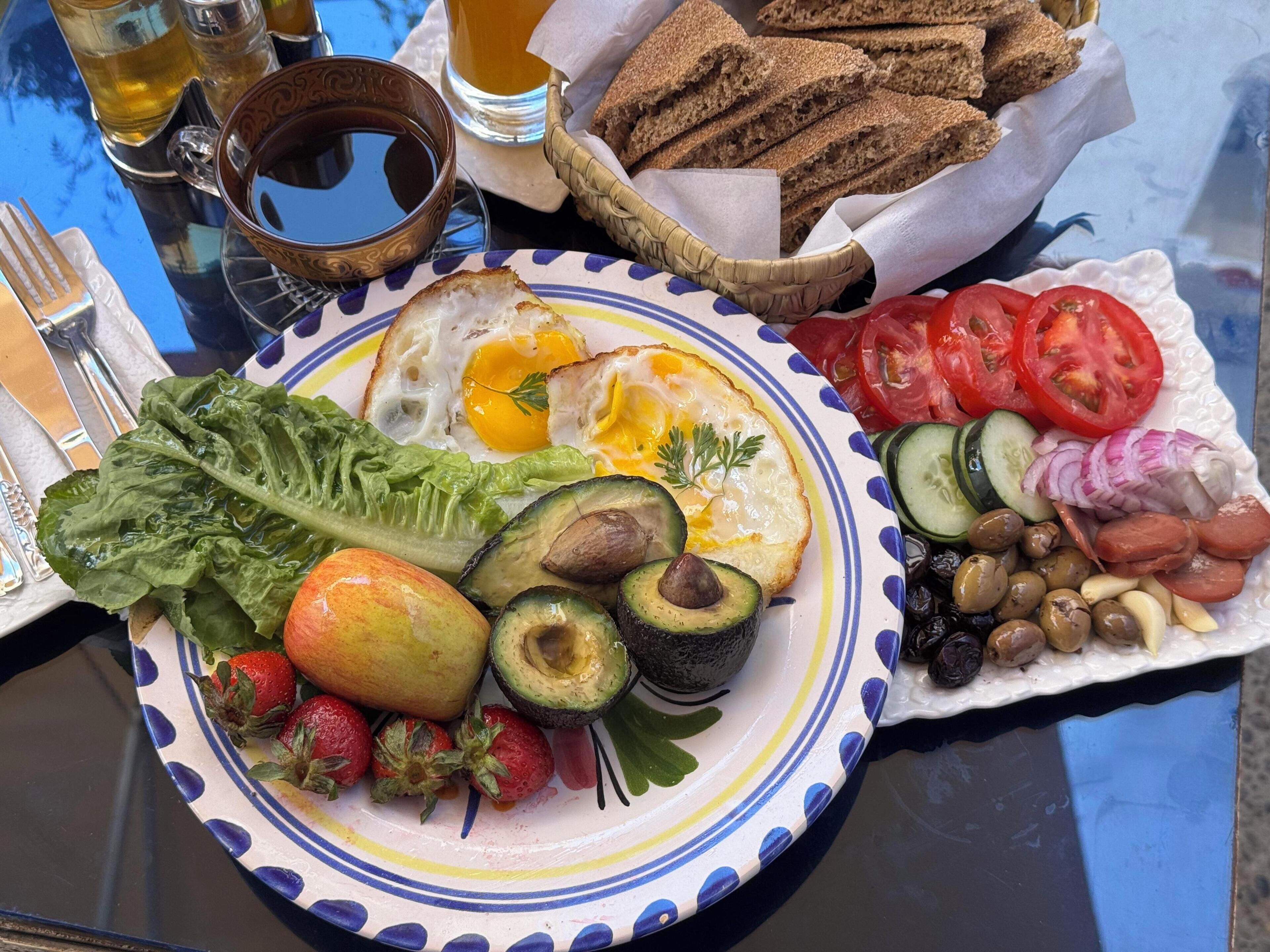 Un plato de desayuno con huevos, aguacate, fresas y verduras.
