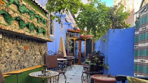Un patio con mobiliario exterior, un muro de piedra y una valla azul.
