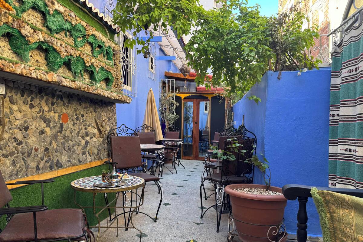 A courtyard with outdoor seating, a stone wall, and a blue fence.