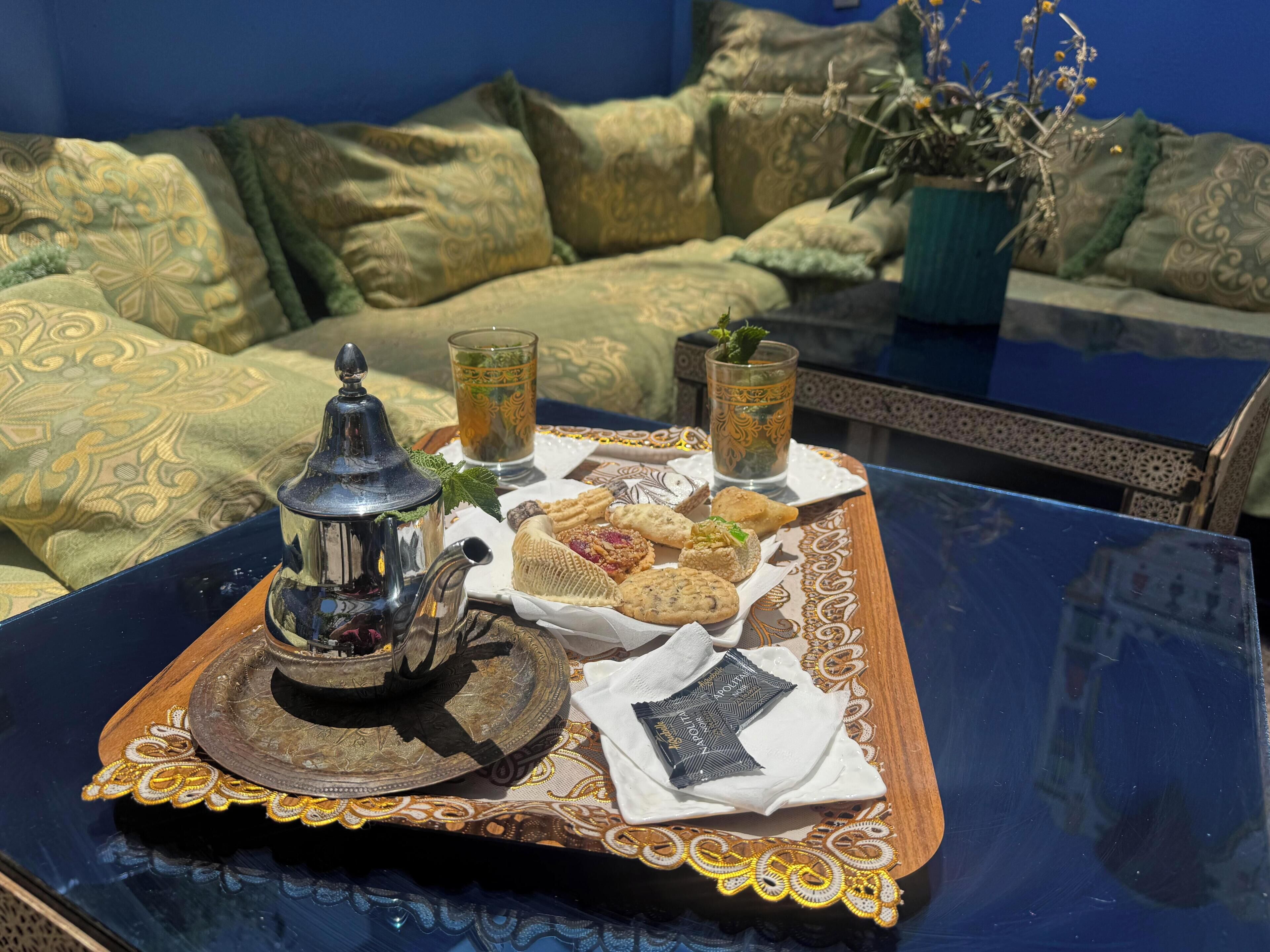 Una bandeja con comida y bebidas sobre una mesa, una tetera y un plato decorativo.